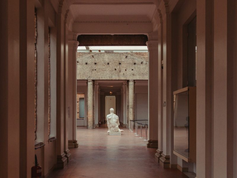 Empty museum hallway with a marble statue at the end